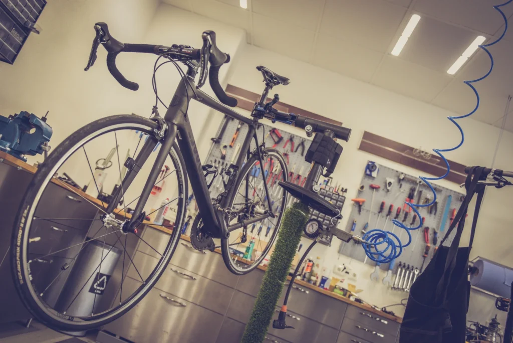 Road bike mounted on a repair stand with workshop tools in the background