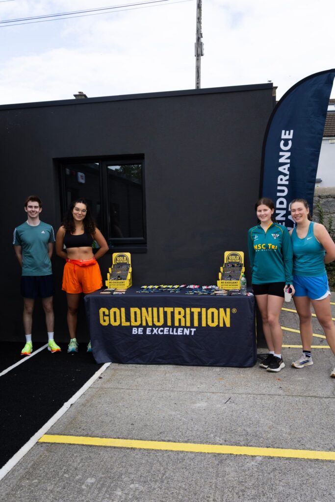 Runners and triathletes standing beside a Gold Nutrition table outside the Endurance Lab studio