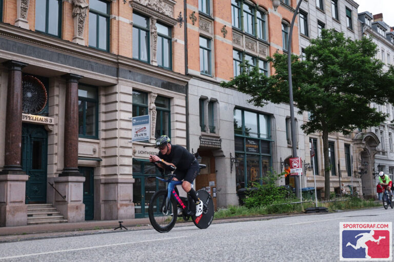 Marc Bennett on the bike leg of an IRONMAN, riding past city buildings