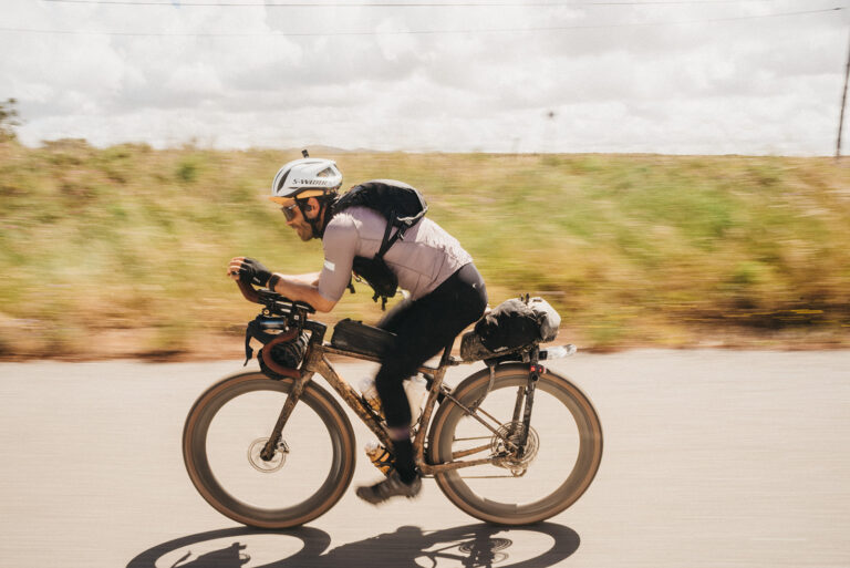 Sílvio Gonçalves riding his loaded gravel bike at speed on a country road during an ultra-distance race